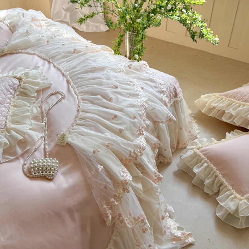 600TC Delicate pink and white bedding with floral embroidery and ruffles on a bed.