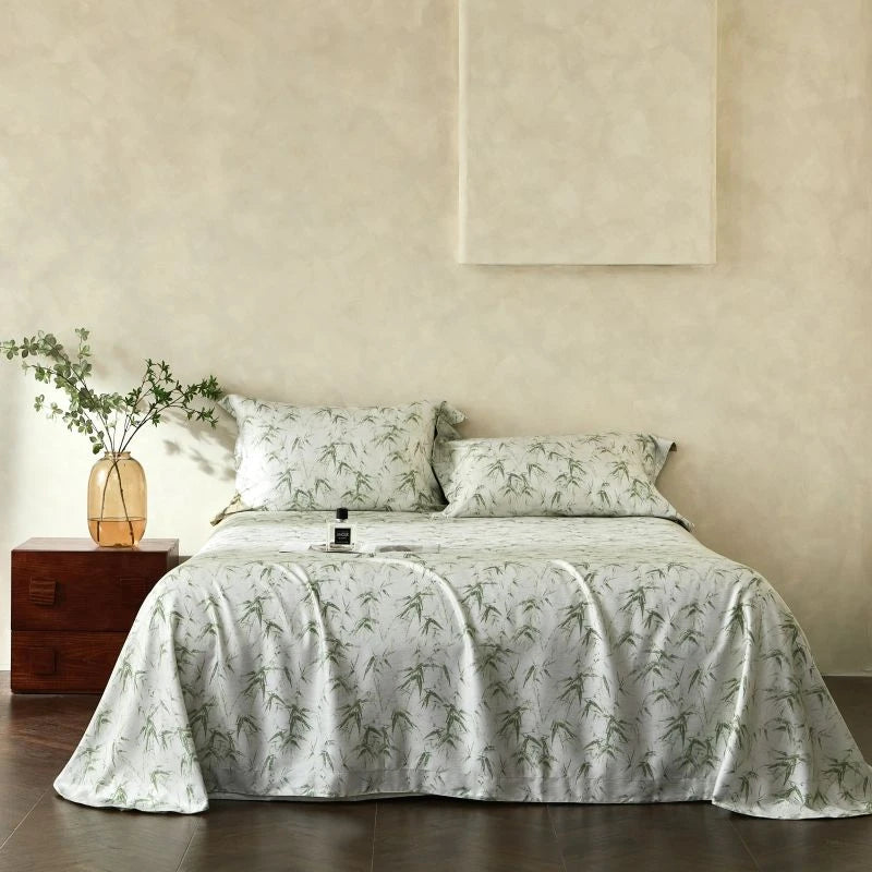 Bed with floral bedding and pillows in a room with a wooden nightstand and plant.