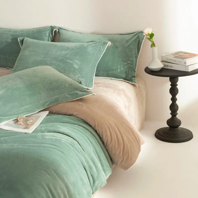 Bed with green bedding and pillows, side table with books and a vase.
