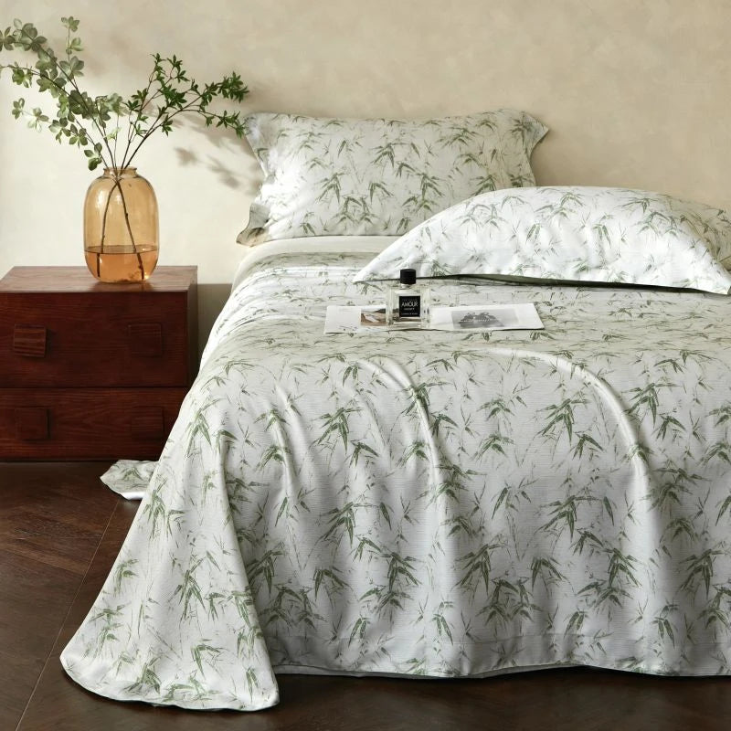 Bed with green leaf patterned bedding in a bedroom setting.