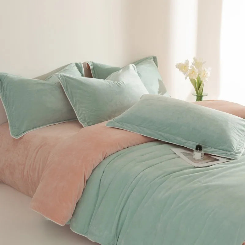 Bed with light green bedding and peach blanket in a softly lit room.