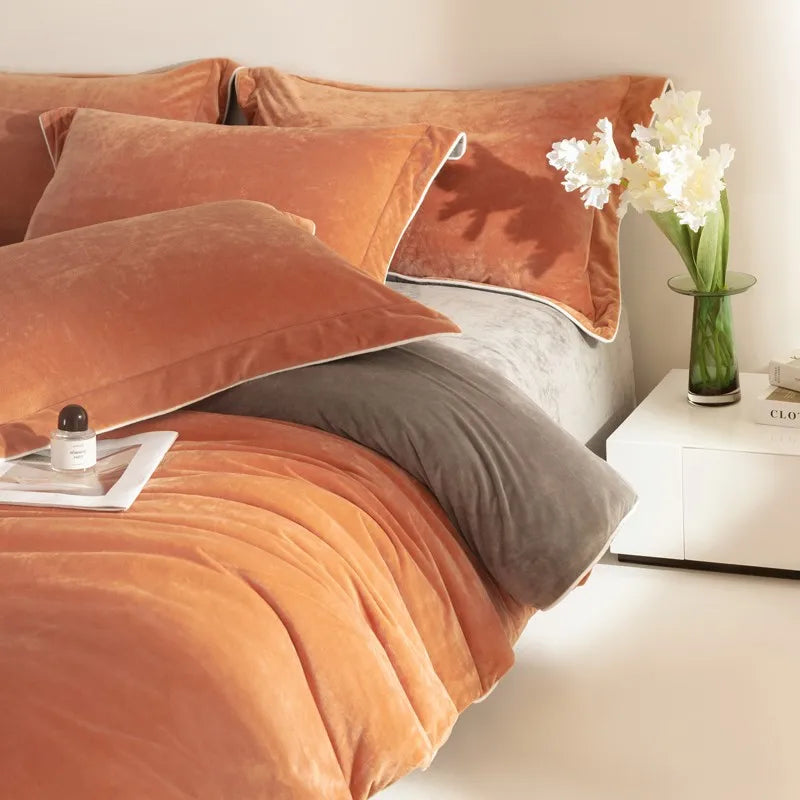 Bed with orange and gray bedding, a nightstand with a vase of flowers, and a magazine.