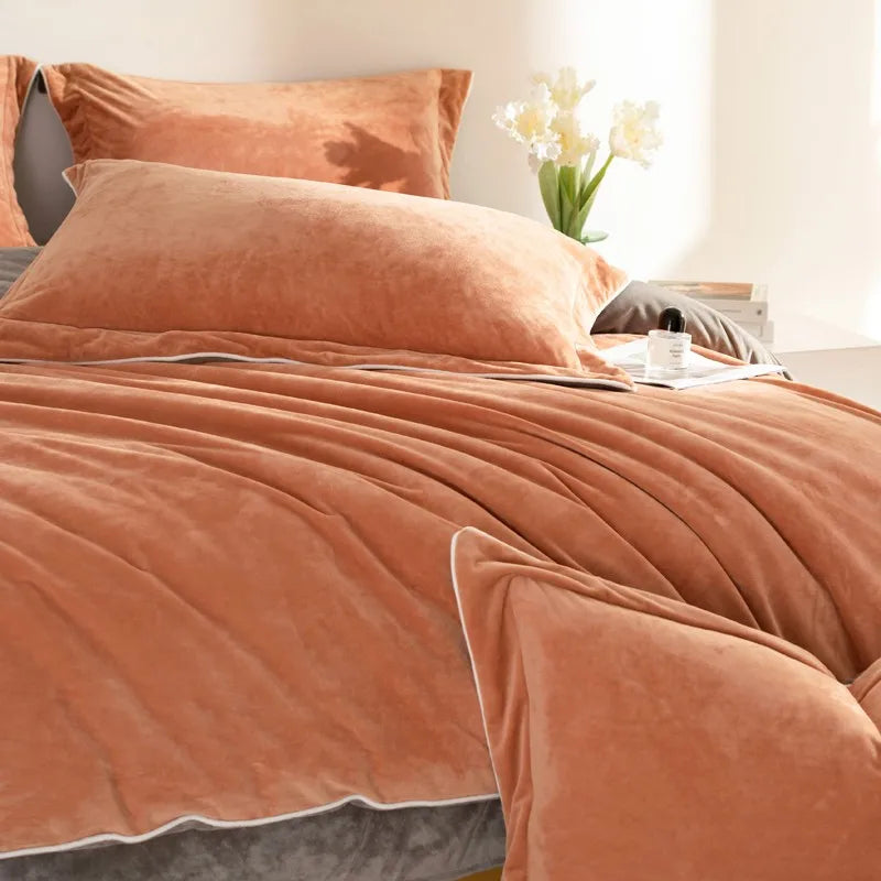 Bed with orange bedding and pillows in a bright room.
