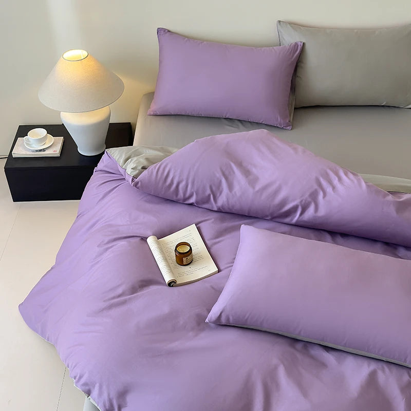 Bed with purple bedding and pillows in a bedroom setting.