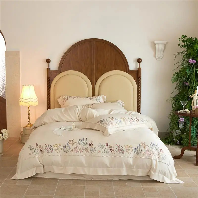 Bedroom with a wooden headboard and floral embroidered bedding.