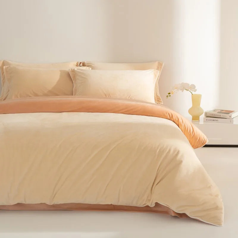 Beige and orange bedding set on a bed with a side table in the background.
