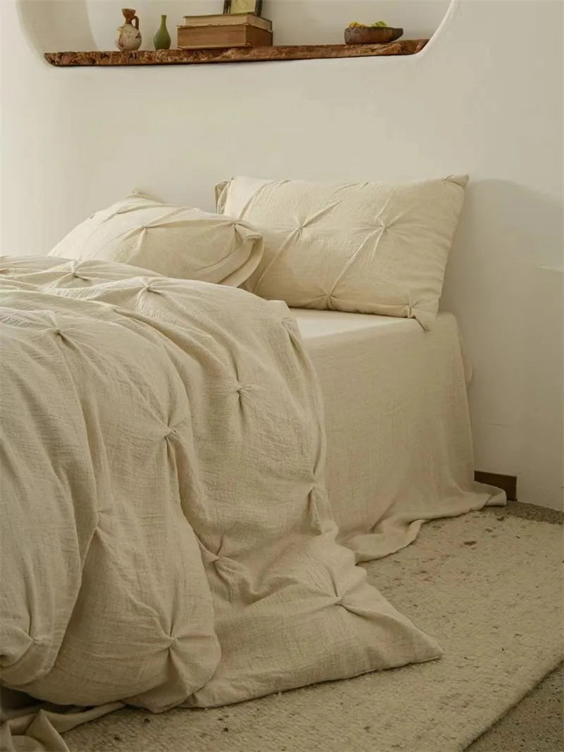 Beige bedding on a bed in a minimalistic room with a shelf in the background.