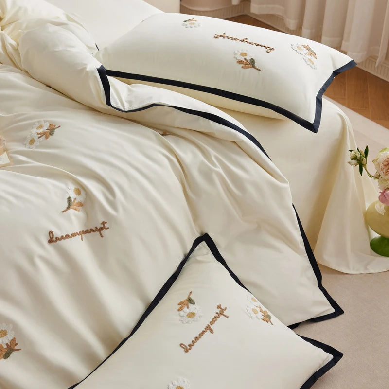 Beige bedding set with embroidered details on a bed in a bedroom setting.