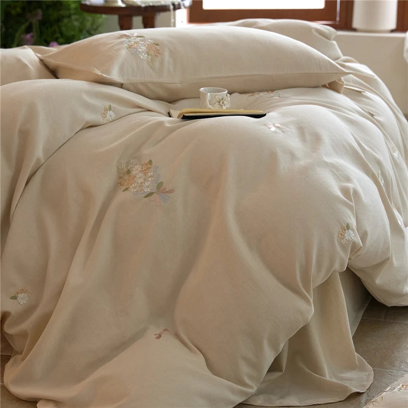 Beige embroidered bedding set on a bed with a blurred background
