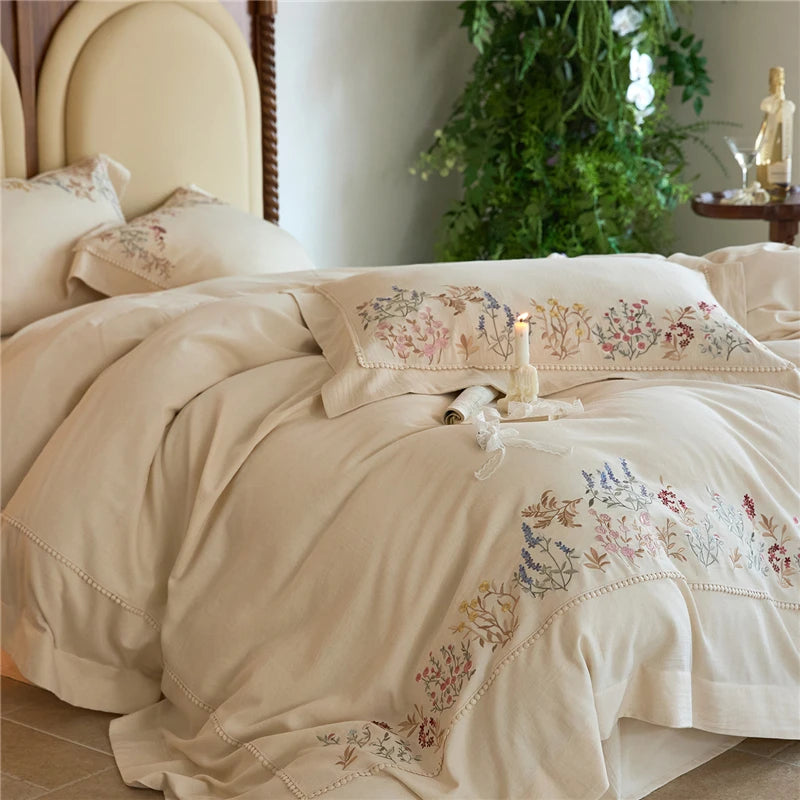 Beige embroidered bedding set on a bed with a decorative pillow cases and duvet cover.