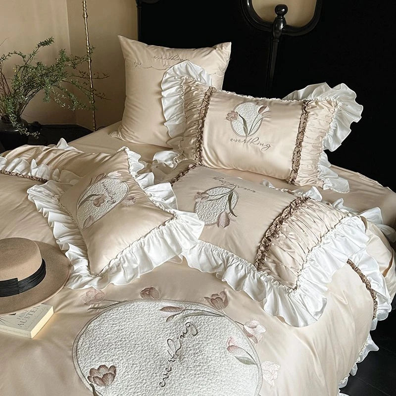 Beige floral embroidered bedding set with ruffled edges on a bed.