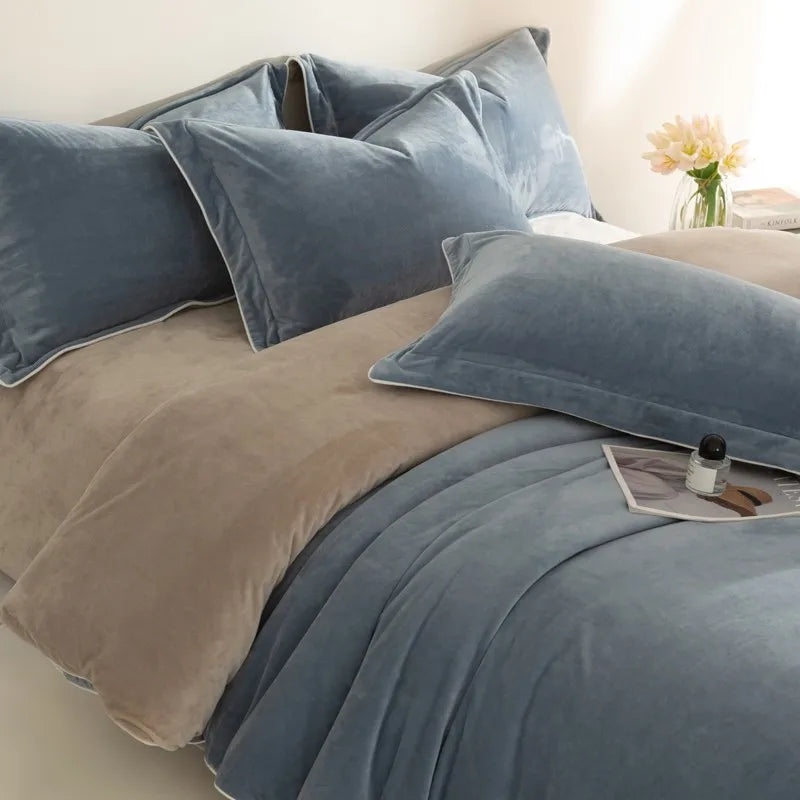 Blue and gray bedding set on a bed with a vase of flowers in the background.