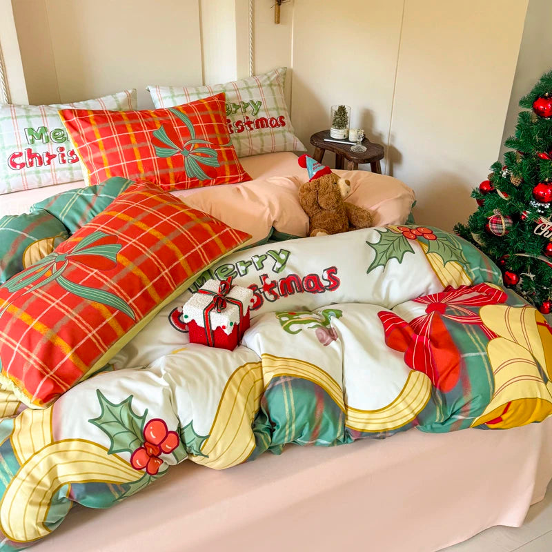 Christmas-themed bedding set with decorative pillows and a teddy bear on a bed, next to a Christmas tree.
