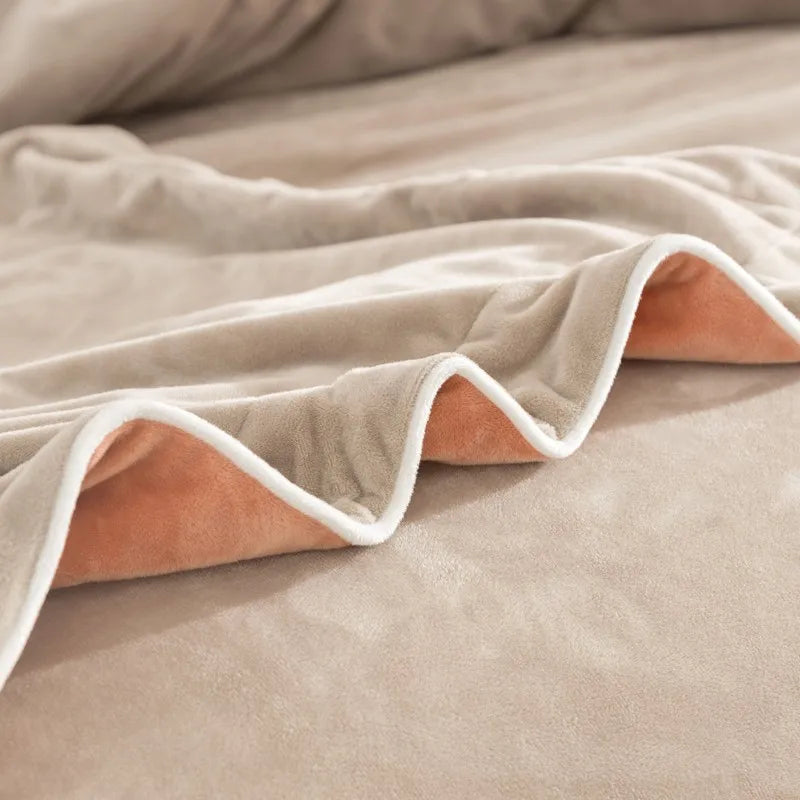 Close-up of a beige blanket with white trim on a bed.