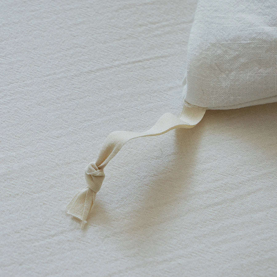Close-up of a textured pillow with a ribbon on a matching fabric background