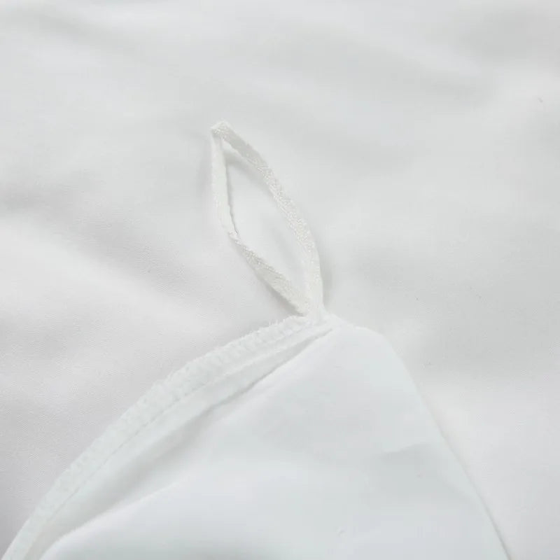 Close-up of a white duvet cover with thin straps on a light gray background
