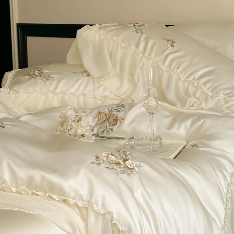 Close-up of a white embroidered bedspread with floral patterns on a bed.