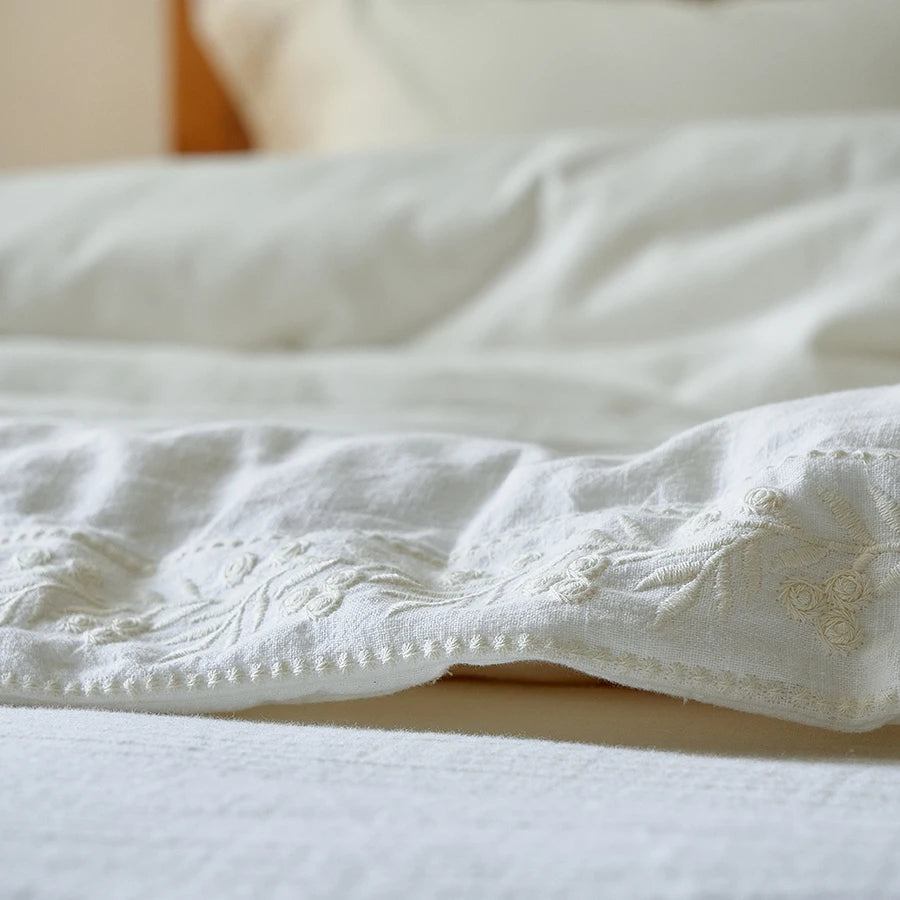 Close-up of a white textured comforter on a bed with a blurred background