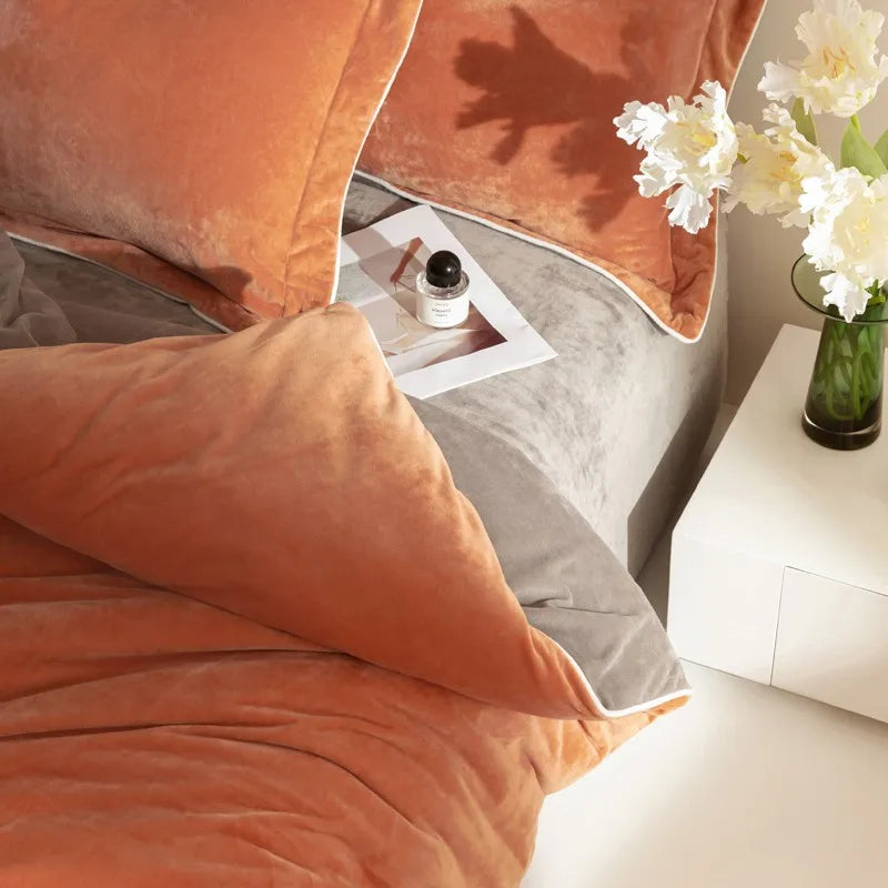 Close-up of orange pillows on a bed with a side table and flowers in the background