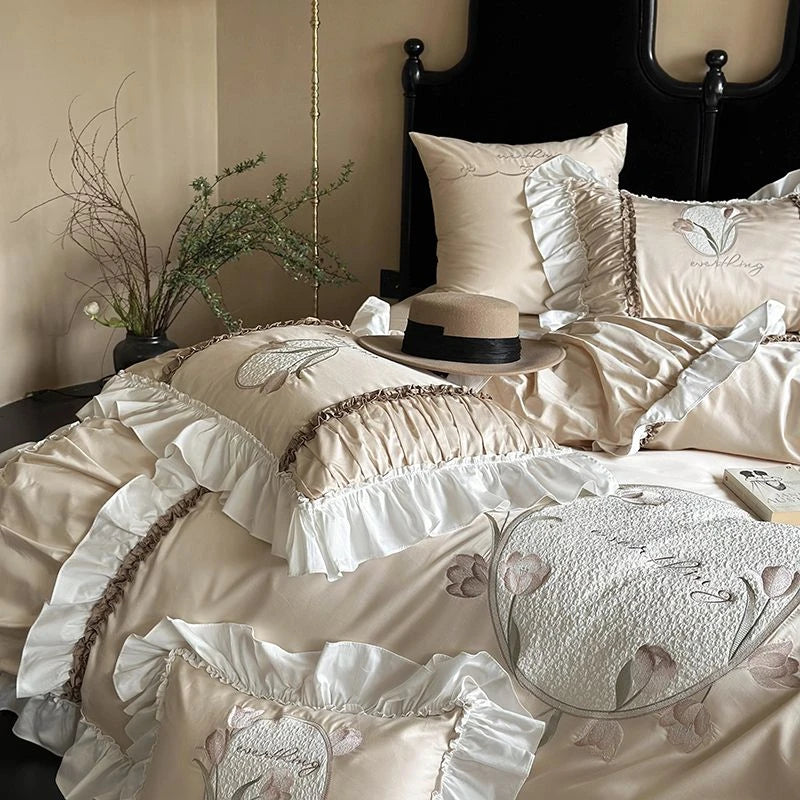 Delicate beige floral embroidered bedding set on a bed with a black headboard.