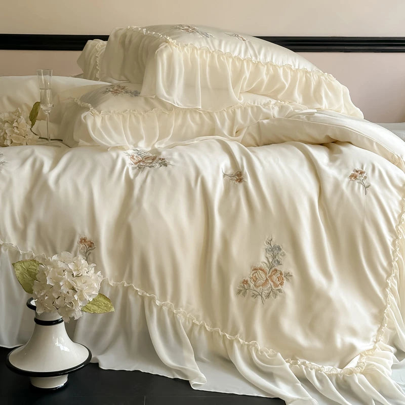 Delicate white bedding set with floral embroidery on a bed.