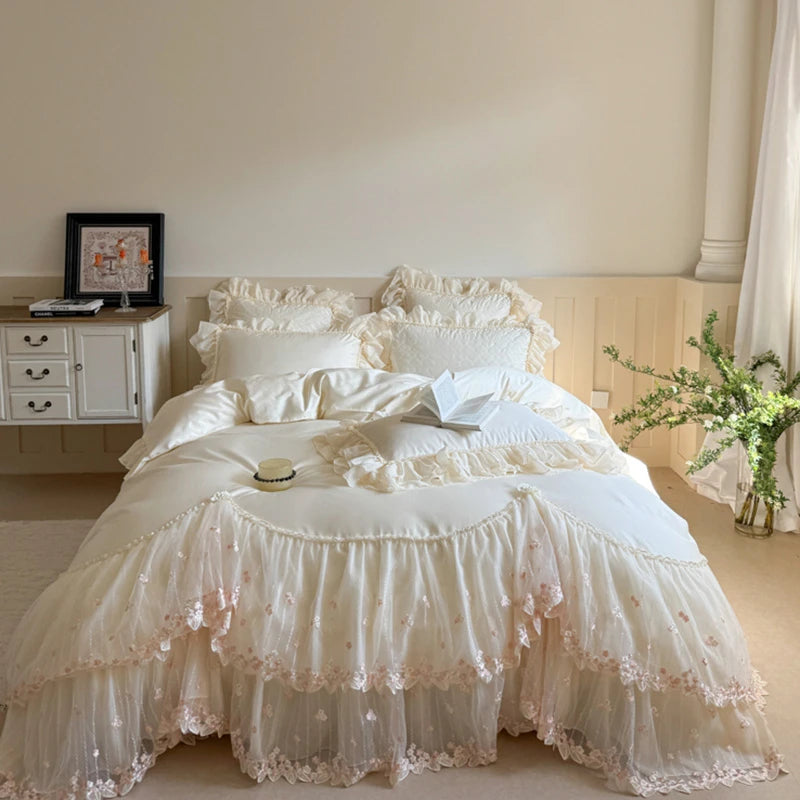 Double size White lace bedspread on a bed in a bedroom setting with a side table and plant.