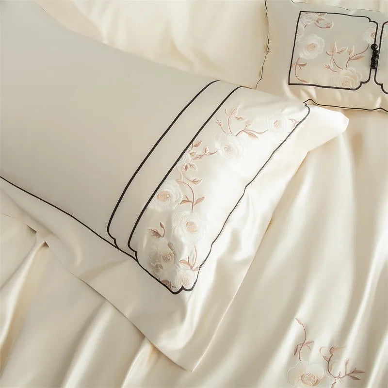 Embroidered bedding set with floral patterns and black piping and fancy pillowcases.