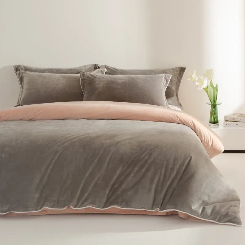 Gray and pink bedding set on a bed with a vase of flowers on a nightstand.