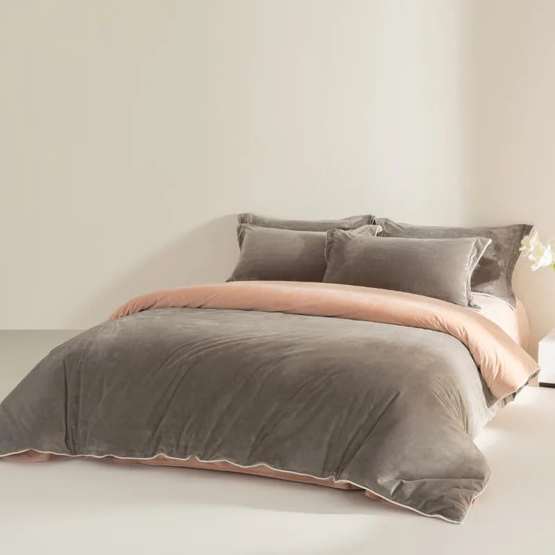 Gray bedding set with peach edges on a bed in a minimalistic room.