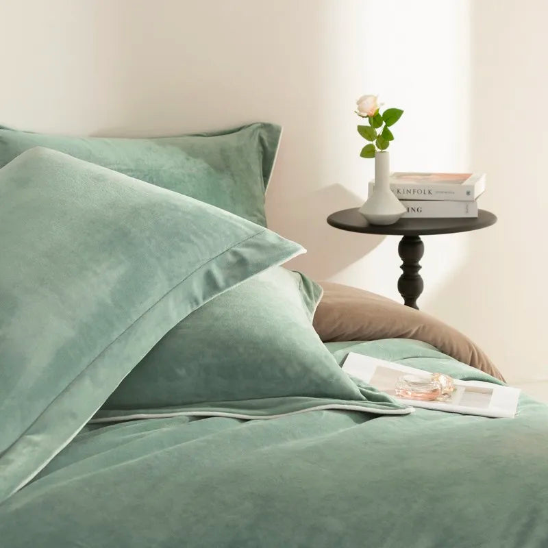 Green bedding set on a bed with a side table in the background