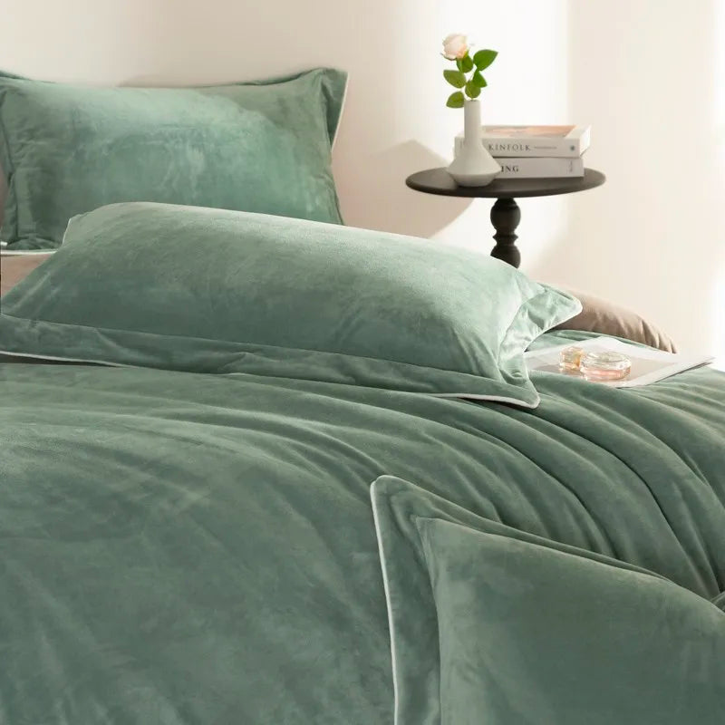 Green velvet bedding set on a bed with a side table in the background.