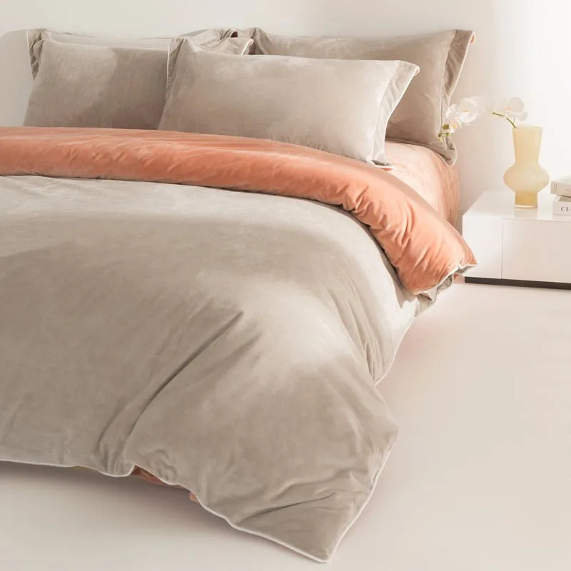 Neatly made bed with beige bedding and pink blanket in a softly lit room.