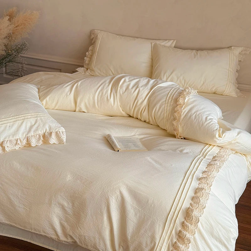 Neatly made bed with cream-colored bedding and pillows in a softly lit room.