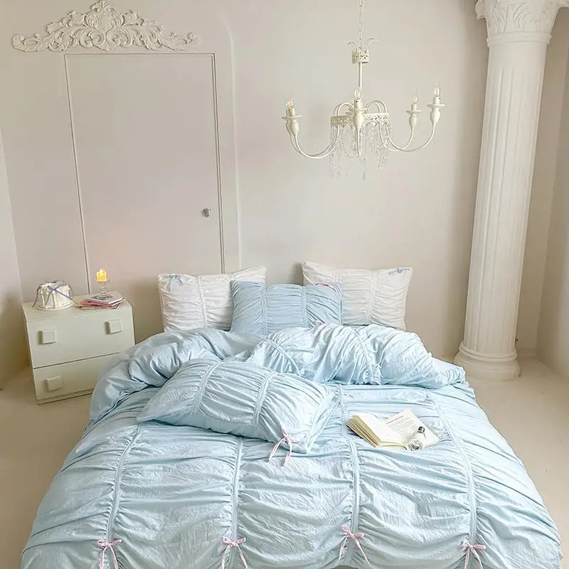 Neatly made bed with light blue bedding in a bedroom setting.
