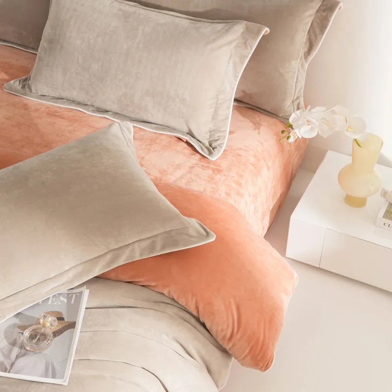 Neatly made bed with orange and gray pillows and a magazine on a nightstand.