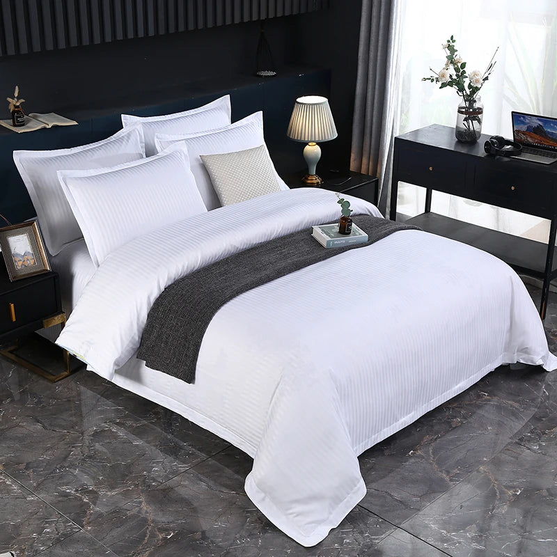 Neatly made bed with white bedding and gray blanket in a bedroom setting.