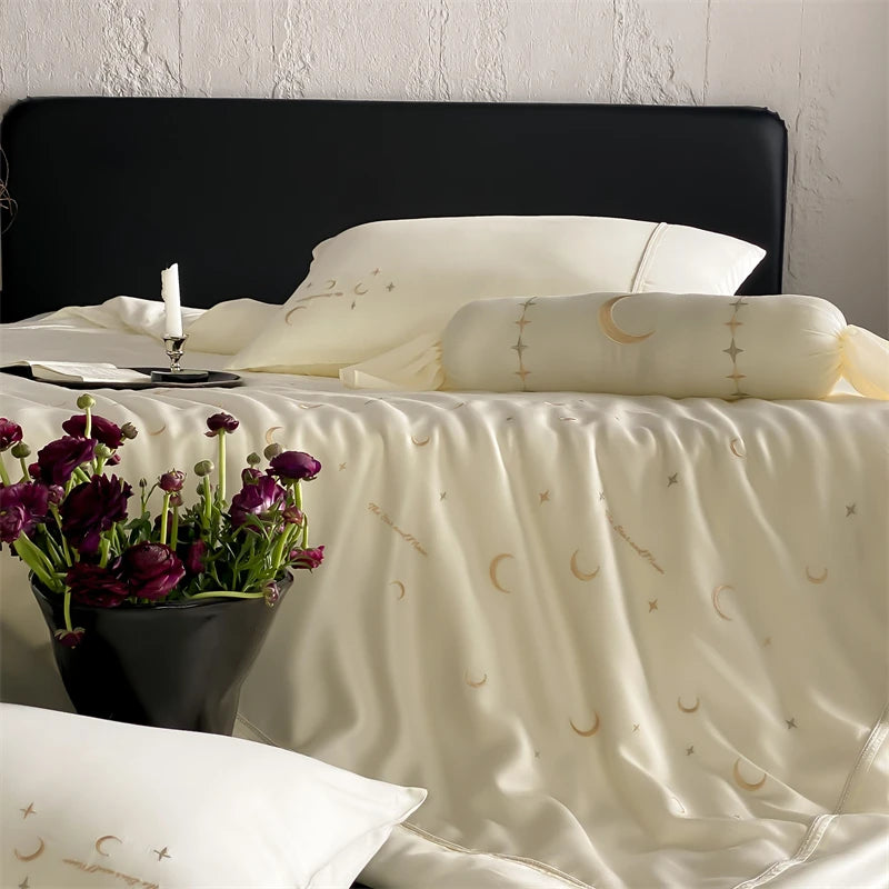 Neatly made bed with white bedding featuring celestial patterns