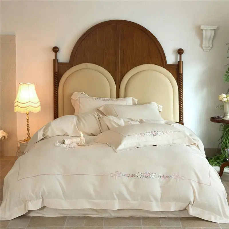 Neatly made bed with white minimalist floral design  bedding and decorative pillows in a bedroom setting.