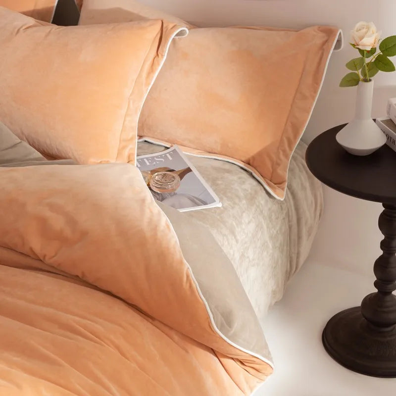Peach-colored bedding set on a bed with a side table and vase in the background.