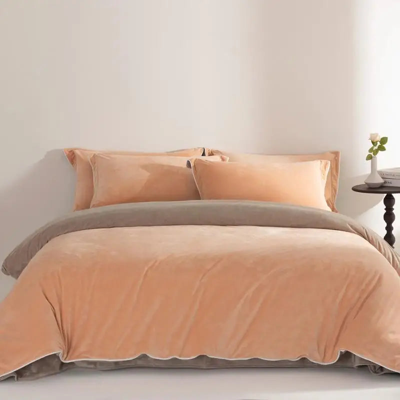 Peach comforter set on a bed with pillows against a plain wall.