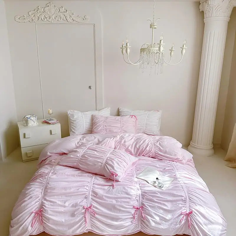 Pink ruffled bedspread with decorative pillows in a bedroom setting.