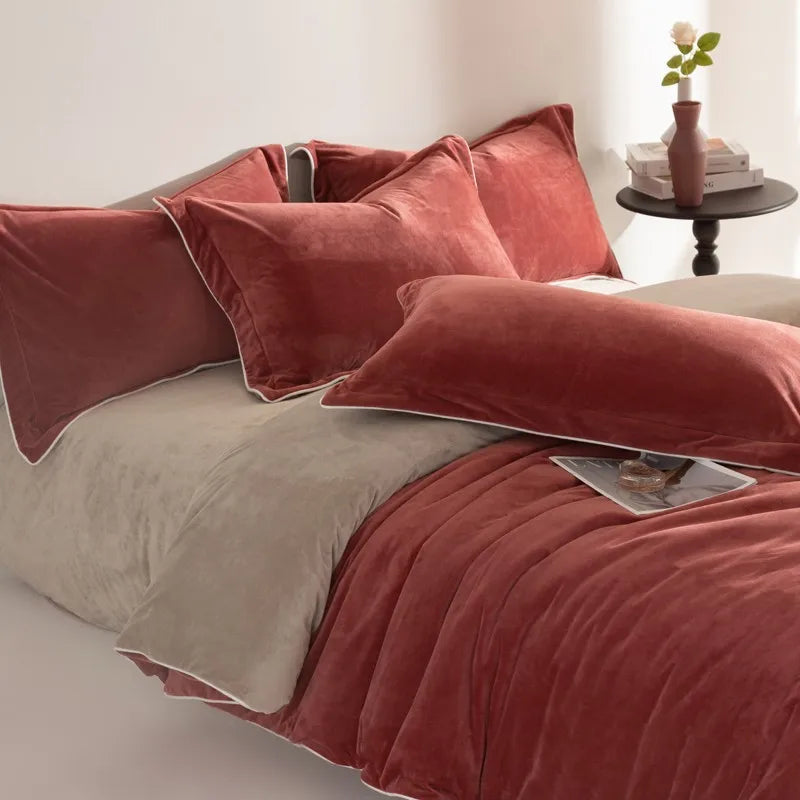 Red rust velvet bedding set on a bed with a side table in the background.