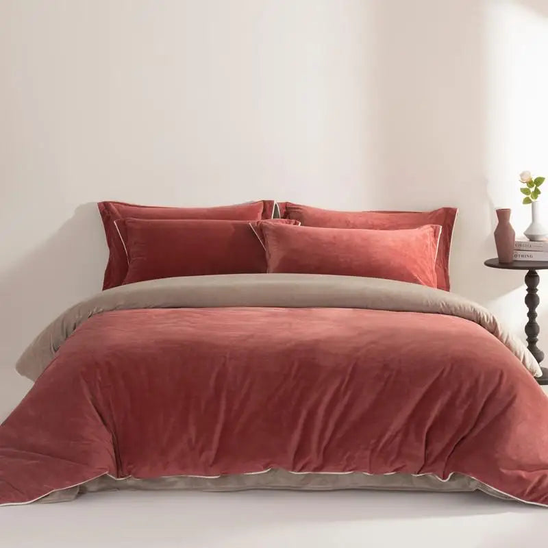 Rust velvet comforter set on a bed with pillows against a white wall.