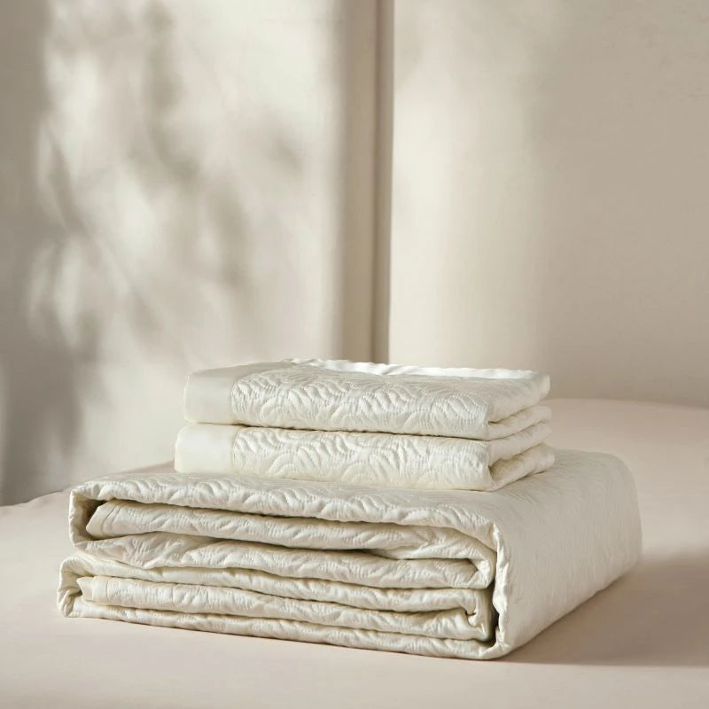 Stack of folded white bedding on a neutral background