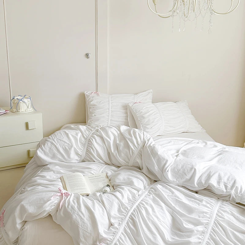 White bedding on a bed in a bedroom with a nightstand and decorative items.