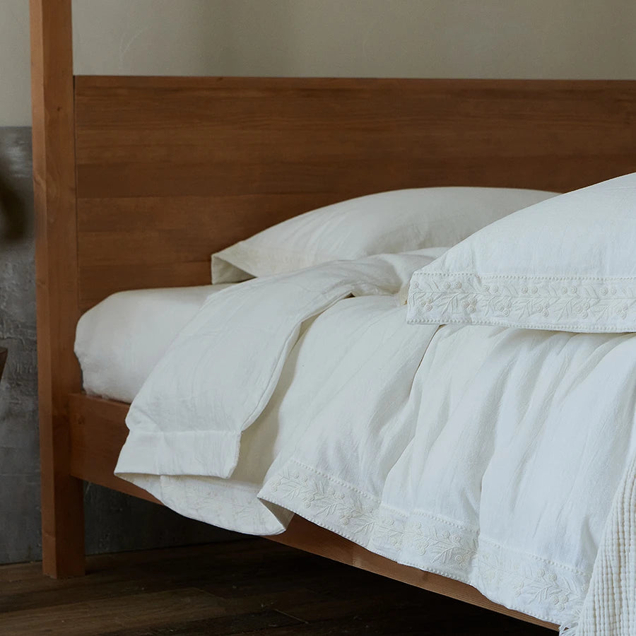 White bedding on a wooden bed frame in a bedroom setting
