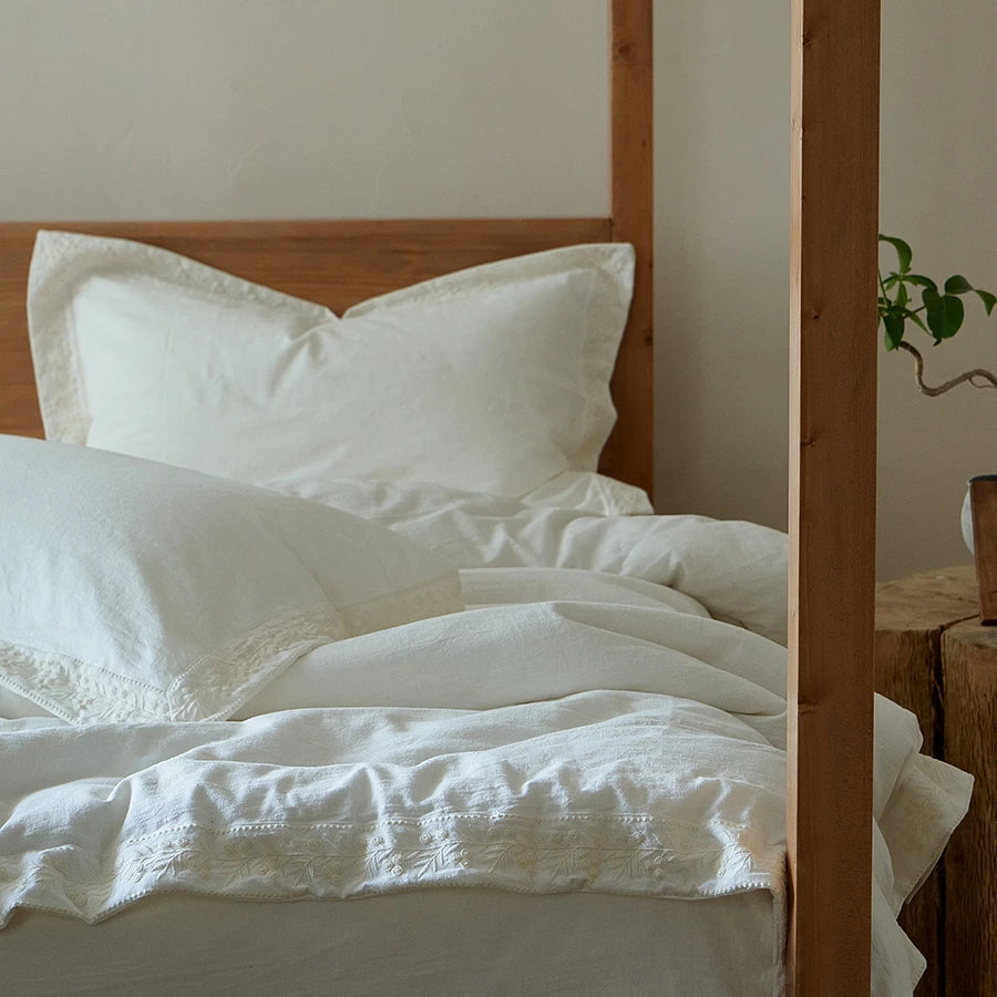 White bedding on a wooden bed with a neutral background