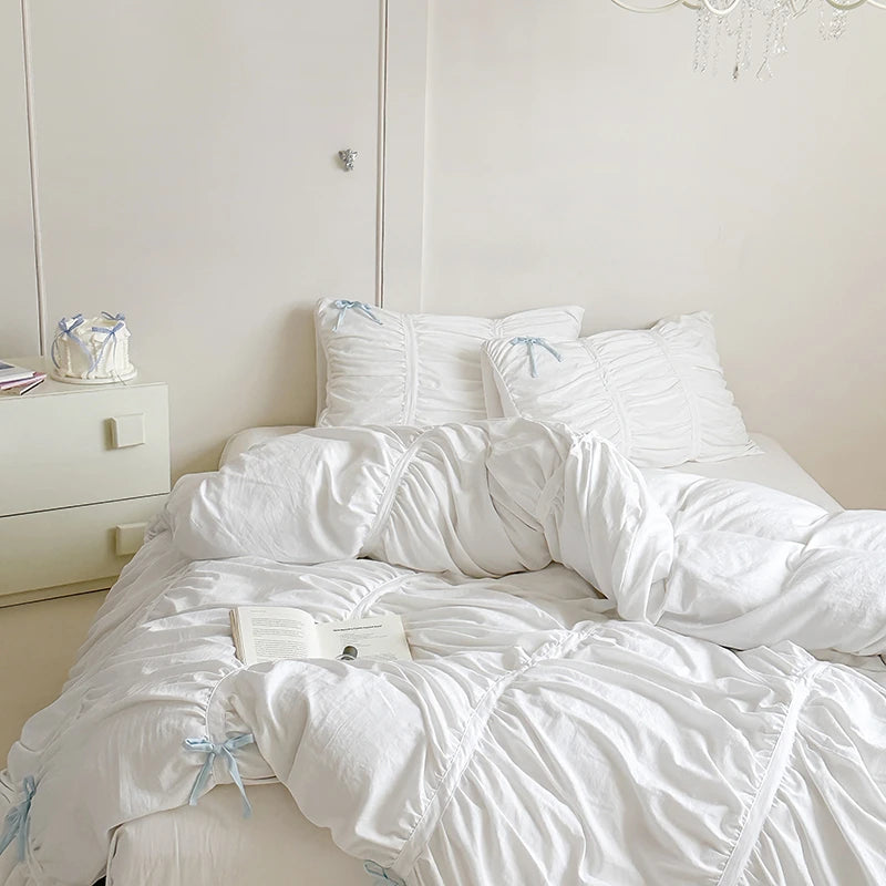 White bedding set on a bed with a nightstand in the background