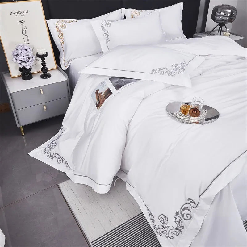 White bedding set with decorative embroidery on a bed in a bedroom setting.