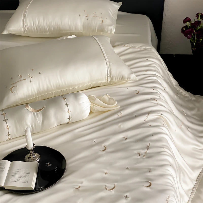 White bedding set with embroidered designs on a bed.